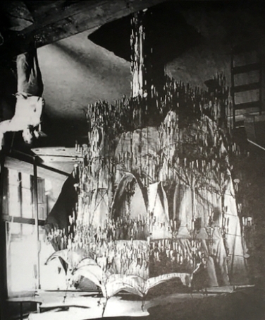 Fotografía en el estudio de Gaudí con un ensayo de catenarias para la formulación de la cúpula estereofunicular (posición normal e invertida) de la iglesia de la colonia Güell, elaborado para calcular las cargas y fuerzas del edificio a proyectar. 
